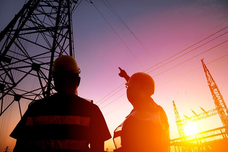 Dos electricistas mirando una torre eléctrica